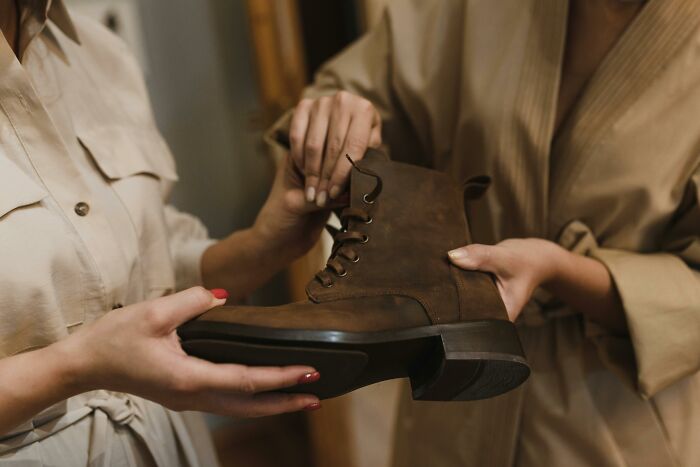 Two people examining a brown boot, focusing on details, highlighting older adults' changed preferences.