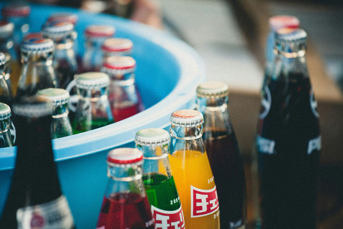 Bottles of colorful soda in a blue bucket, showcasing a real-life cheat code for cooling drinks efficiently.