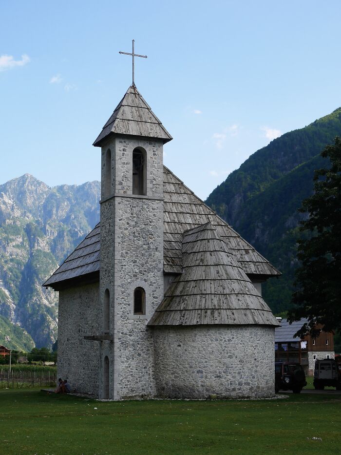 Stone church with a wooden roof set against a mountainous landscape, capturing fascinating church architecture.