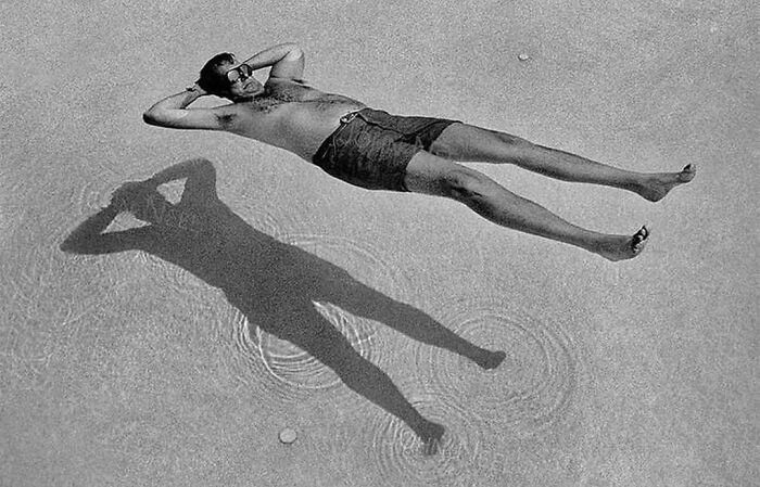 Man lying on water creating a shadow, showcasing one of the most interesting images for an Instagram page.