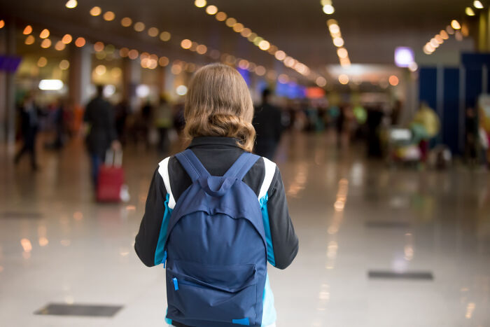 Person with a backpack standing in a bustling airport, capturing intriguing facts from daily life.