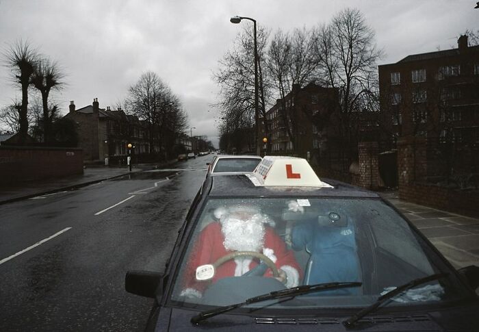 Santa Claus figure in a driving school car on a rainy street; interesting image selection.