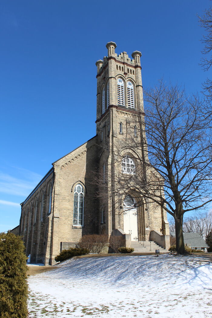 Historic stone church under a clear blue sky, surrounded by winter landscape.