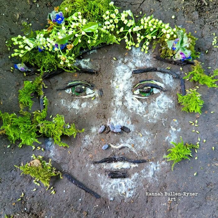 Earth art portrait of a face made from moss, flowers, and natural materials on the ground.