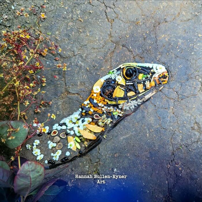 Animal portrait of a snake created using natural materials arranged on a stone surface.