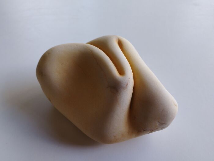 Smooth stone sculpture with a soft, folded appearance, resembling fabric, defies physics.