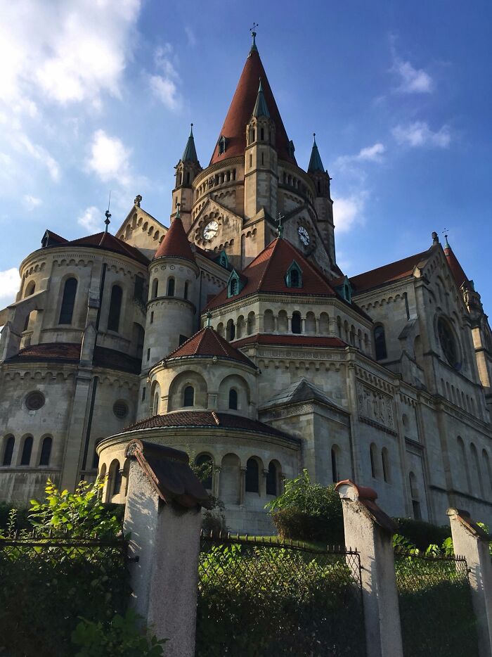 Majestic church with intricate architecture and red-roofed towers against a blue sky.