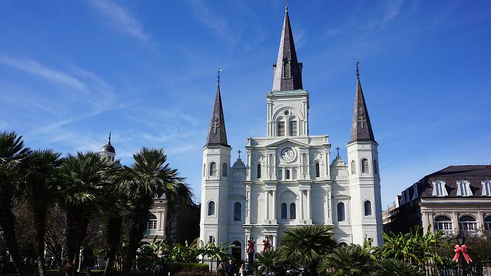 Majestic church with towering spires and ornate facade under a clear blue sky, featuring beautiful landscaping.