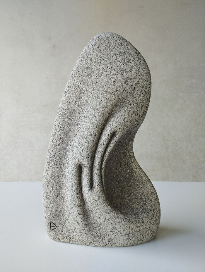 Abstract stone sculpture with a smooth, fluid shape, appearing to defy physics with its soft, fold-like curves.