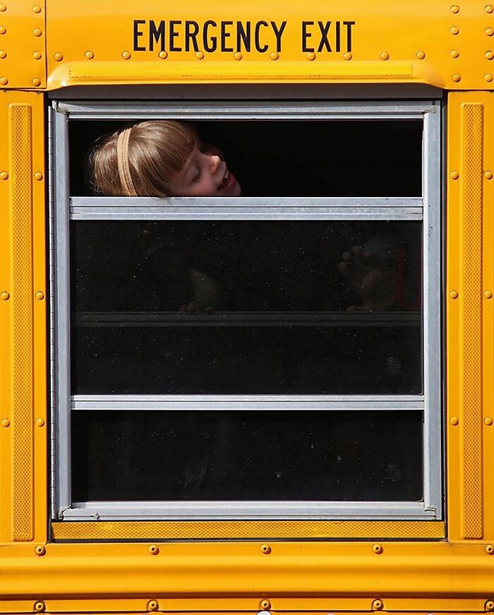 Child peeking through a school bus emergency exit window, showcasing an interesting moment.