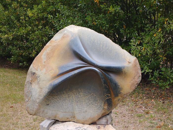 Sculpture resembling soft folds in stone, showcasing physics-defying artistry in a natural setting.