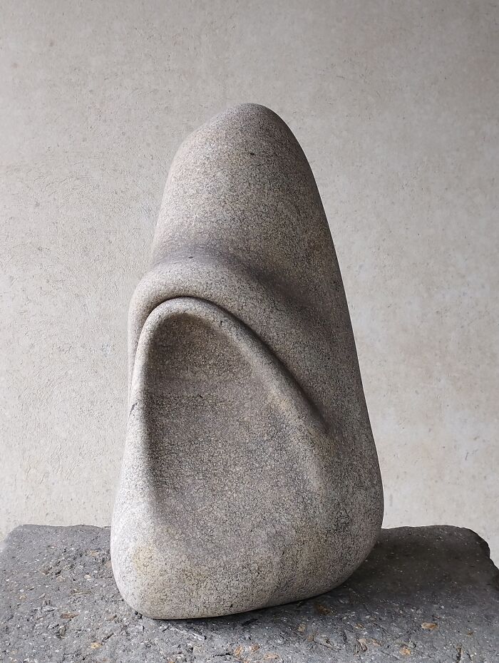 A smooth stone sculpture with flowing curves, appearing soft, defying physics.