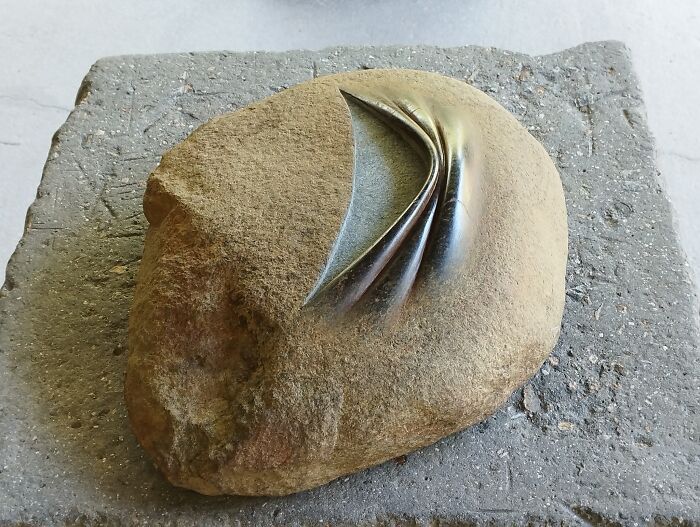 Stone sculpture with a smooth, folded design, showcasing a balance that defies the laws of physics.