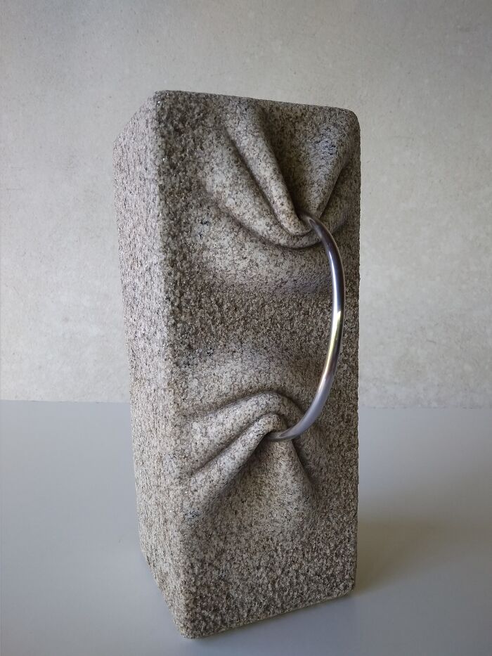 A stone sculpture with a metal ring appears soft, defying physics with its unique design.