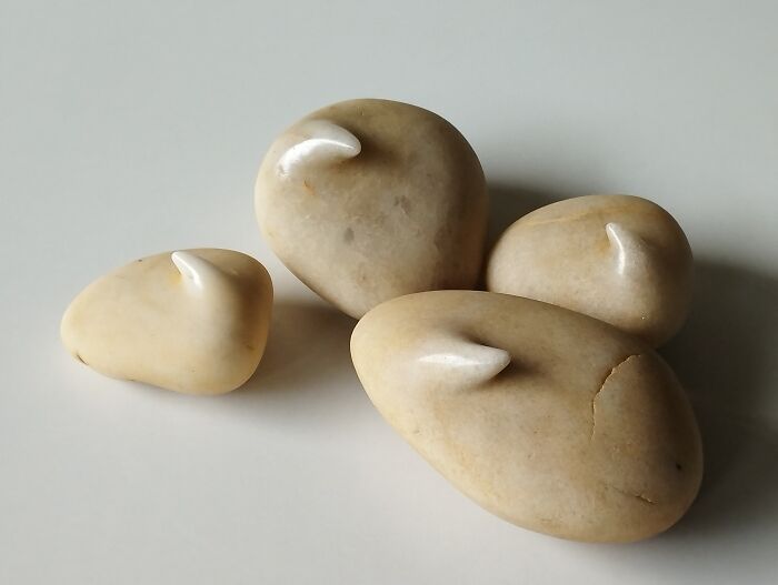 Smooth stone sculptures with horn-like protrusions defy physics on a white surface.