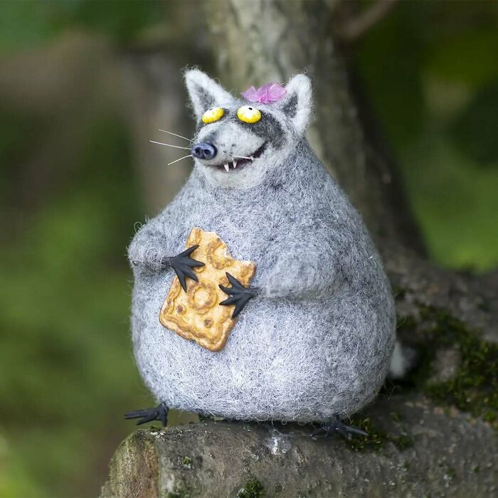 Funny-looking art doll depicting a raccoon-like animal, created by a Georgian artist, holding a cracker.