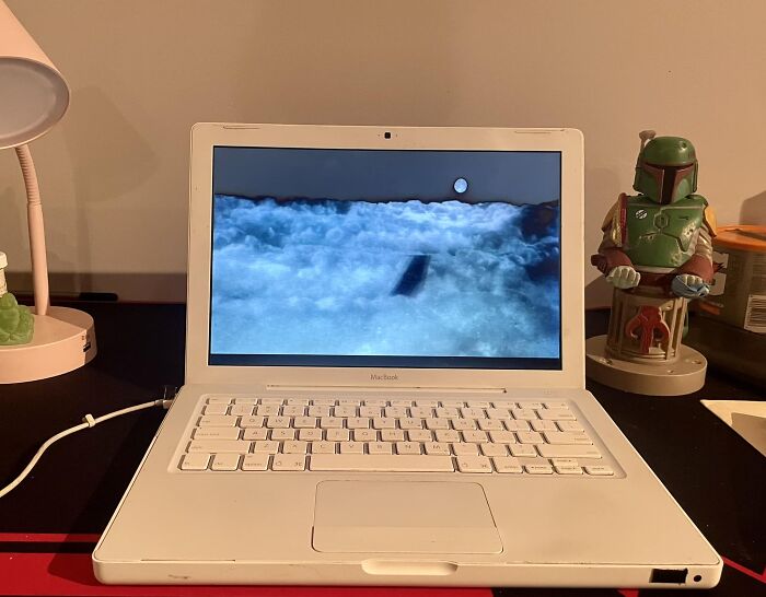 Gen X humor: old laptop showing cloudy screen with collectible toy beside it.