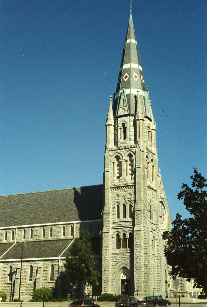 Tall church steeple against a clear blue sky, showcasing fascinating architecture in daytime.