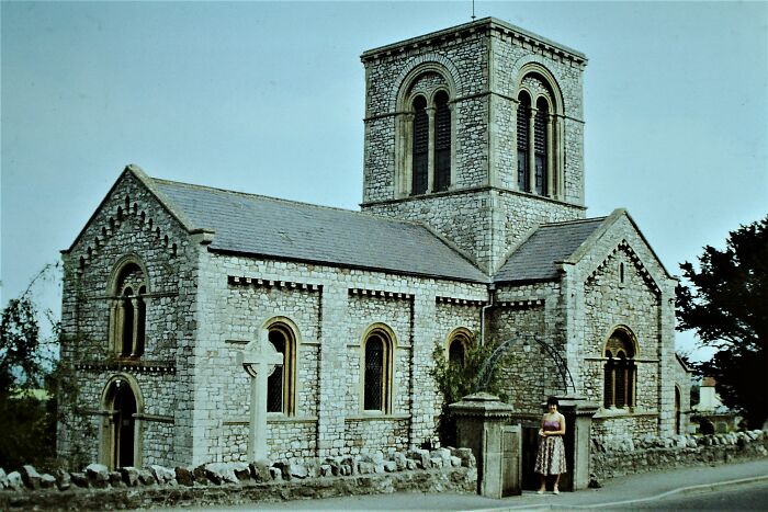 Stone church with arched windows and tower, surrounded by greenery, capturing the essence of fascinating church architecture.