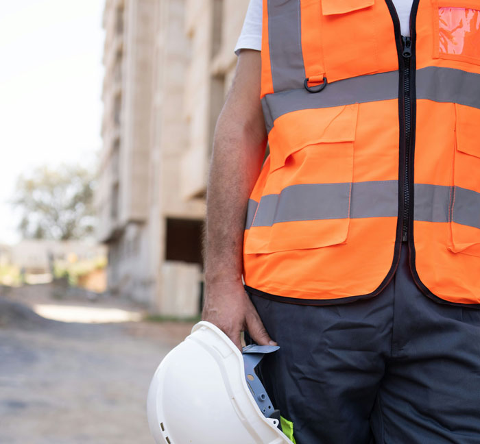 Construction worker in an orange safety vest holding a helmet, demonstrating quality hacks for real-life efficiency.