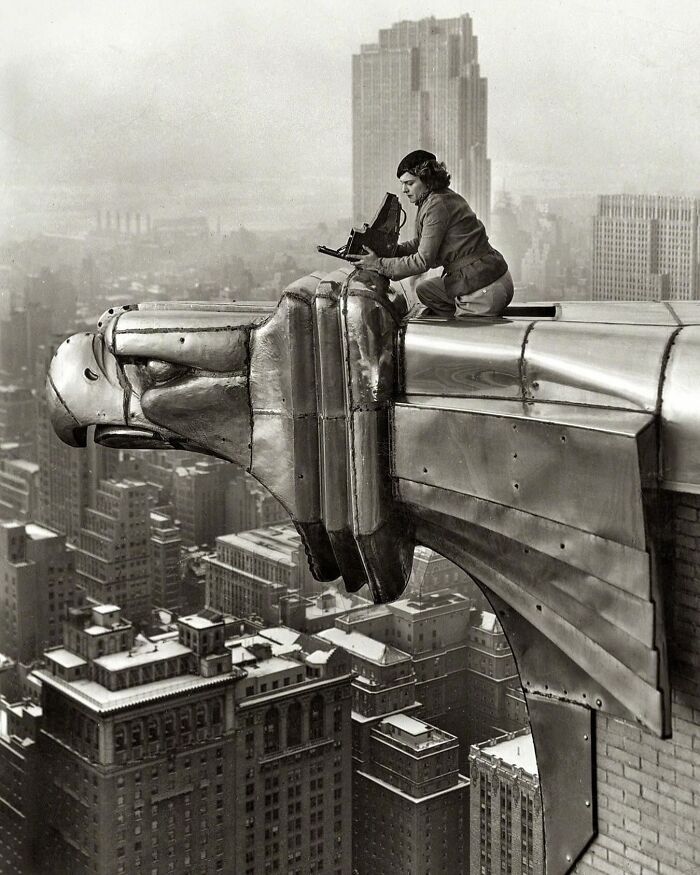 Person perched on a skyscraper ledge photographing the cityscape, embodying an interesting image from an Instagram page.