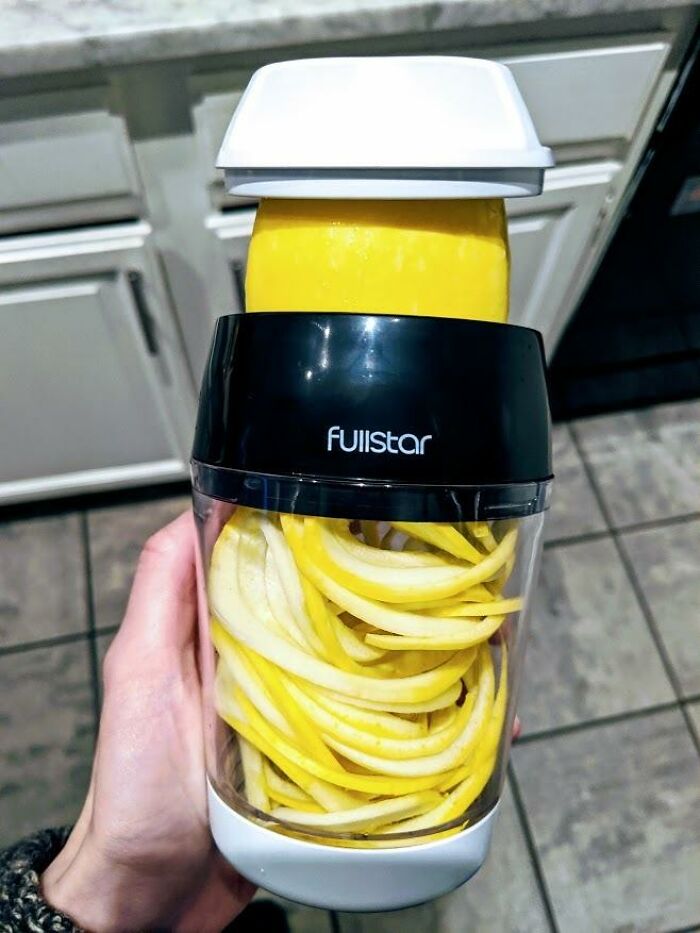 Hand holding a Fullstar spiralizer with spiralized yellow squash, aiding in getting better at cooking.