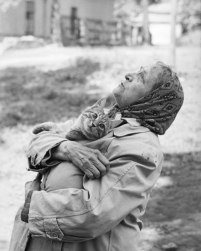 Elderly woman in a headscarf holding a relaxed cat, showcasing interesting images from an Instagram page.