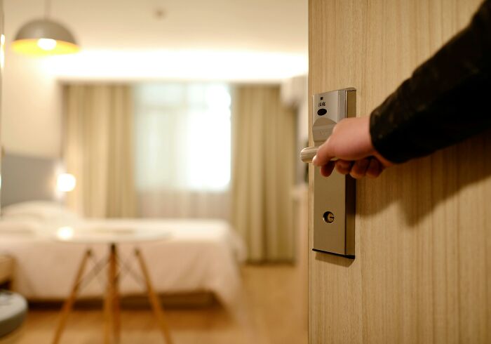 Person opening a hotel room door, suggesting entry without permission as an unethical life hack.