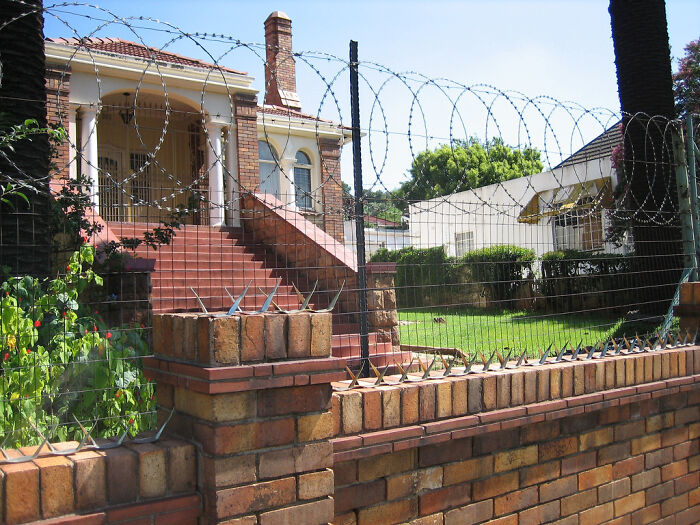 Urban hell scene with a wire fence and a brick house in the background.