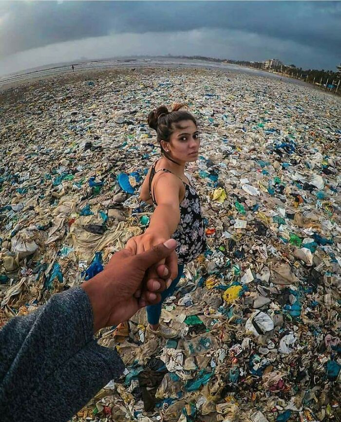 Person walking across trash-covered beach, showcasing an urban hell scene with polluted environment.