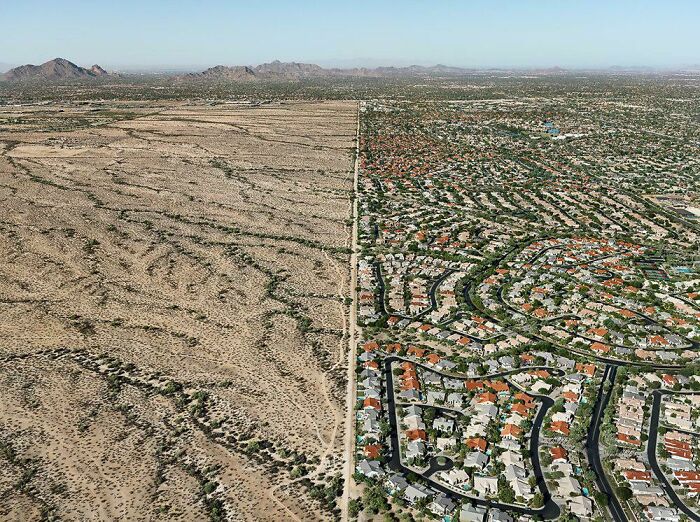 Aerial view showing stark contrast between urban sprawl and barren desert, depicting elements of urban hell.