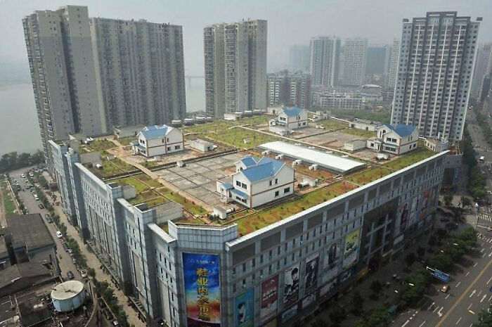 Urban hell example: Rooftop houses on a large city building surrounded by high-rise apartments.