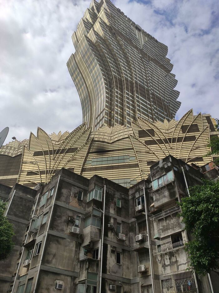 Urban hellscape showing contrast between decaying lower building and modern towering structure above.