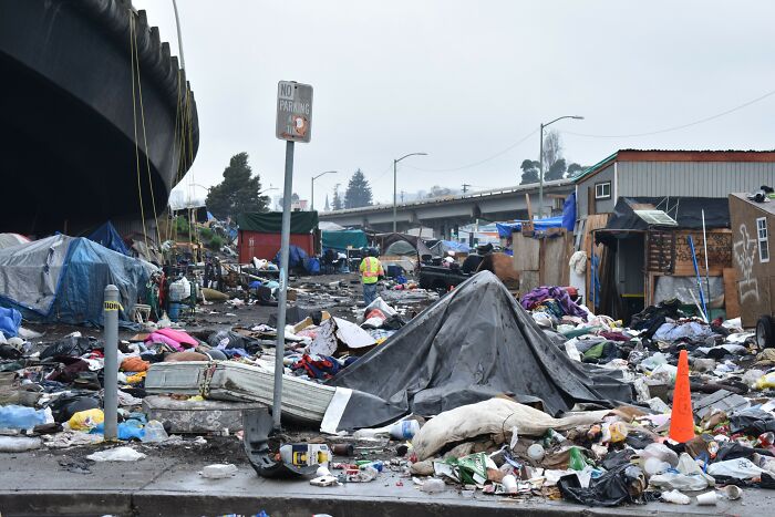 Urban scene with litter and debris scattered under a highway overpass, highlighting environmental challenges.