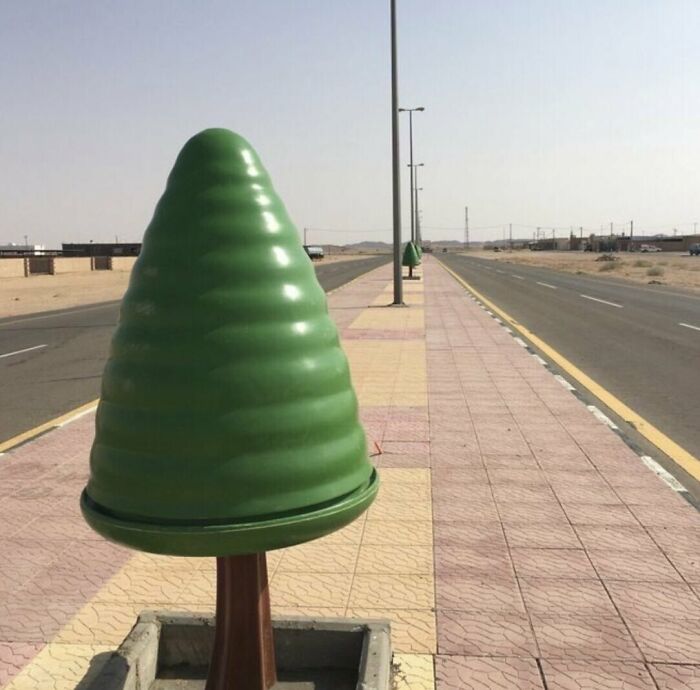 Green plastic tree on deserted urban road, illustrating urban hell concept.