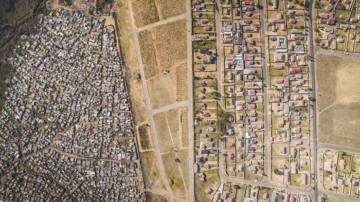 Aerial view of urban hell contrast: densely packed informal settlement versus organized residential area.