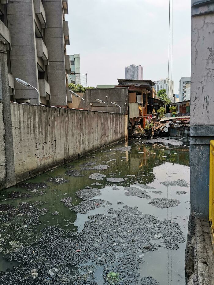 Urban hell scene with polluted water and derelict buildings in a deteriorating city environment.