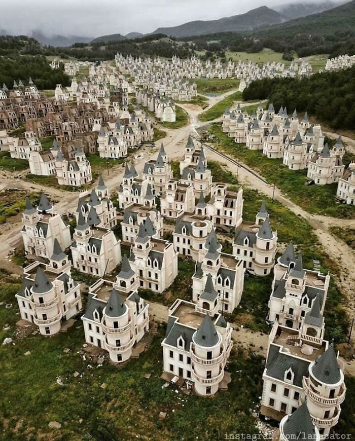 Abandoned castle-like houses in an eerie landscape, exemplifying urban hell with repetitive unfinished structures.