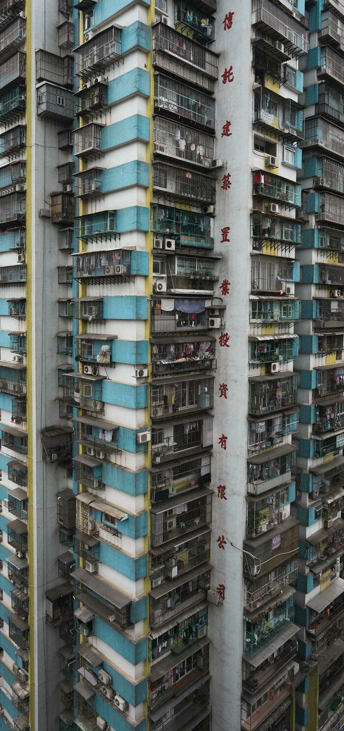 Tall, crowded apartment building showcasing urban hell with numerous air conditioners and metal railings.