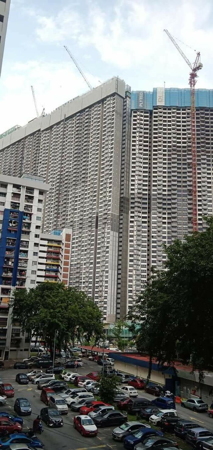 Tall, densely packed apartment buildings with construction cranes amid urban sprawl, representing urban hell.