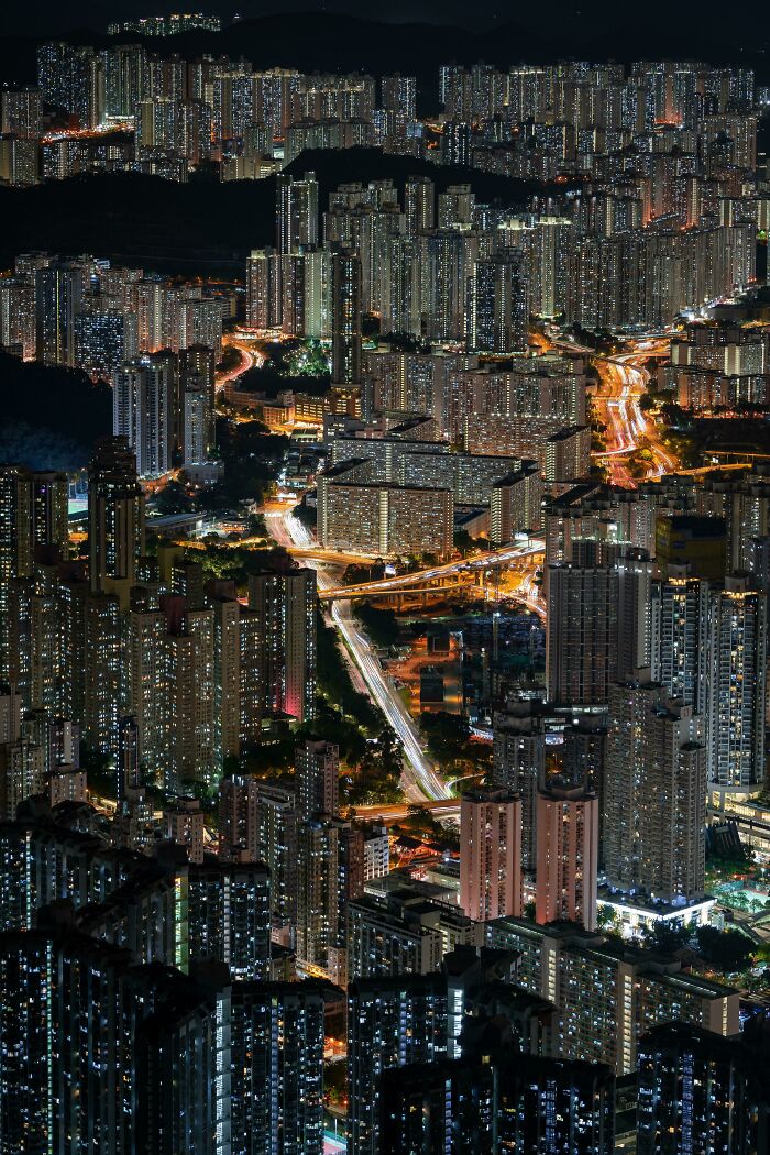 Sprawling urban landscape at night with dense high-rise buildings and illuminated roads, depicting an 'urban hell' scenario.