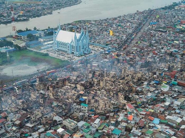 Aerial view of urban hell with densely packed buildings and a large church near a river.