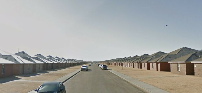 Urban hell scene with identical brick houses lining a deserted street, evoking a sense of desolation.