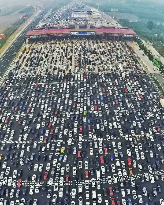 Aerial view of urban hell with a massive traffic jam at a toll booth, cars densely packed for miles.