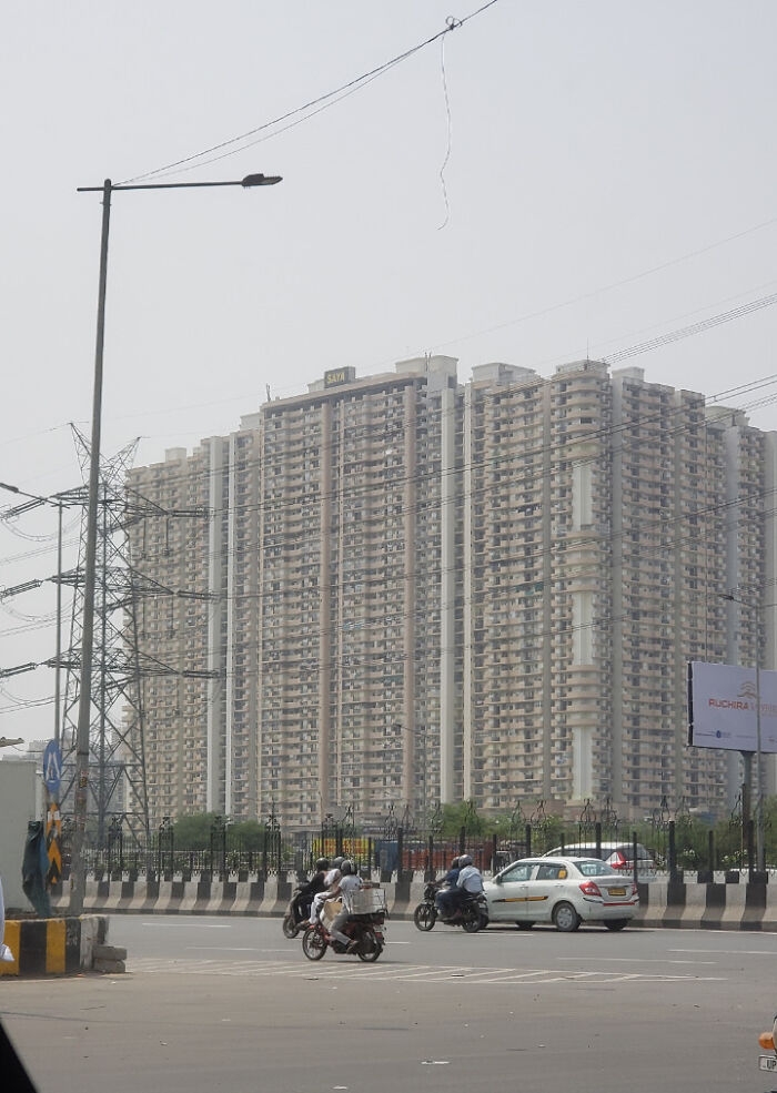 Urban architecture with high-rise buildings, power lines, and vehicles on a road.