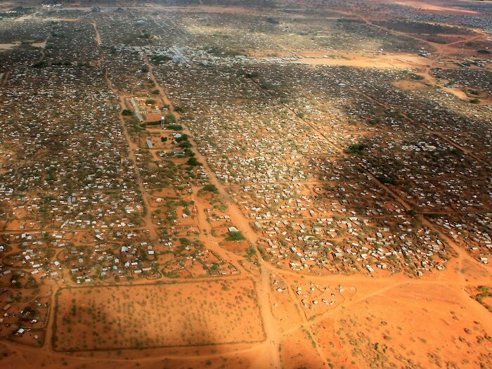 Aerial view of densely packed structures on arid landscape, depicting urban hell conditions.