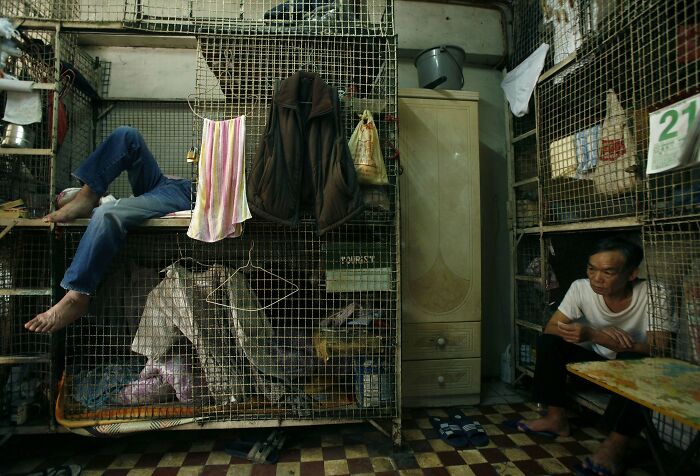 Urban hell example: cramped metal cages with people inside, depicting harsh living conditions in an overcrowded city.