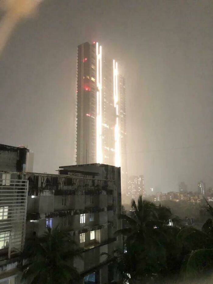 Tall skyscraper illuminated at night, capturing an eerie aspect of urban hell under a gloomy sky.