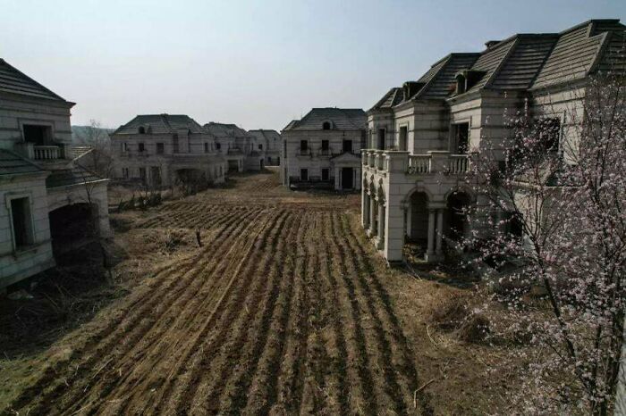 Abandoned urban area with decaying buildings and overgrown fields, illustrating urban hell.