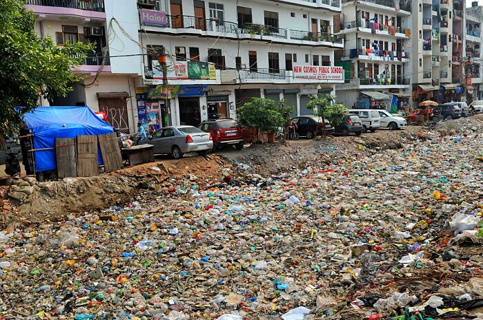 Urban hell scene with a street filled with trash, adjacent to a row of residential buildings and parked cars.